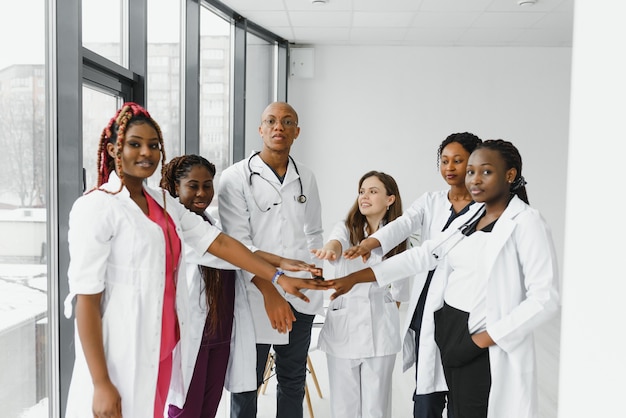 Groupe de médecins mettant les mains ensemble en clinique