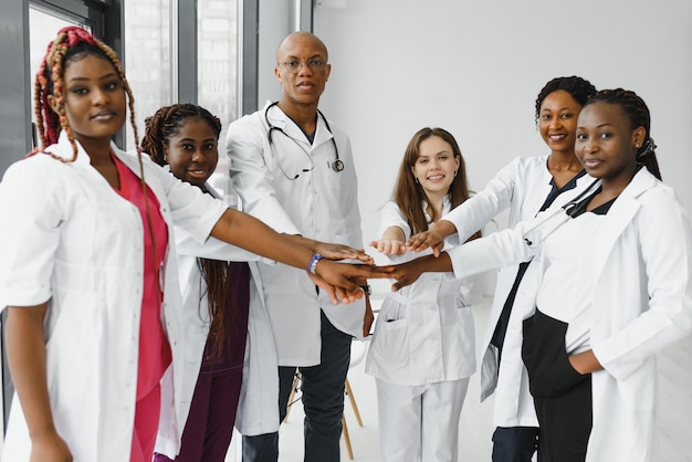 Groupe de médecins mettant les mains ensemble en clinique.