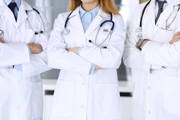 Groupe de médecins modernes debout en équipe avec les bras croisés dans le bureau de l'hôpital en gros plan