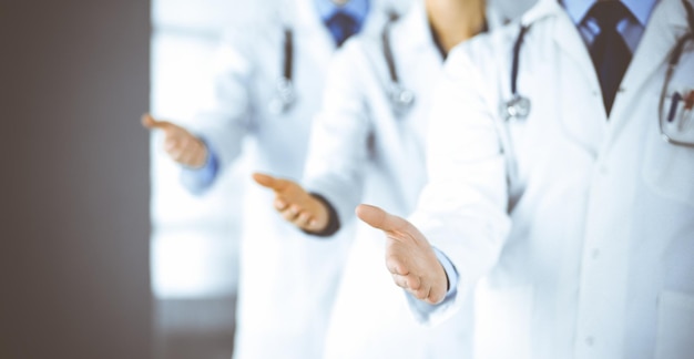 Un groupe de médecins modernes inconnus fait équipe avec les mains ouvertes dans un bureau d'hôpital. Des médecins prêts à examiner et à aider les patients. Aide médicale, assurance soins de santé, meilleur traitement des maladies et