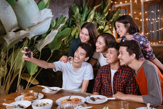 Le groupe des meilleurs amis asiatiques prend un selfie avec un smartphone tout en organisant une garden-party