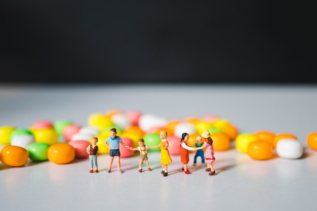 Groupe miniature d&#39;enfants debout fond de bonbons colorés