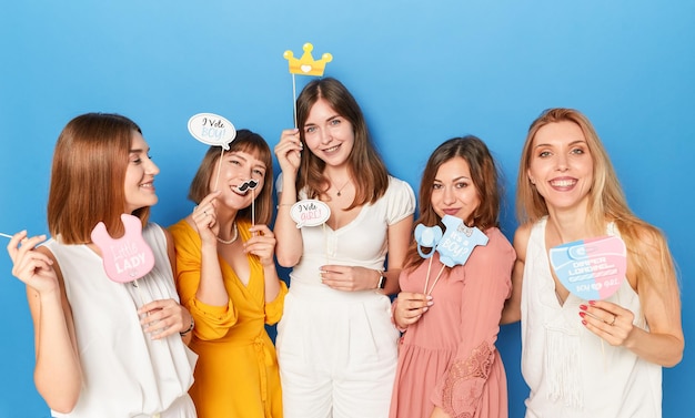 Un groupe de modèles féminins caucasiens souriants pour avoir le sexe révèle un arrière-plan bleu isolé