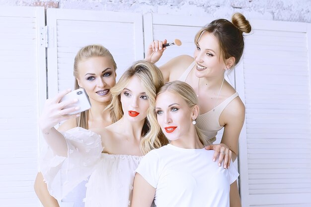 groupe de modèles maquillage / quatre filles avec maquillage professionnel posant en studio, une fête de belles filles amies