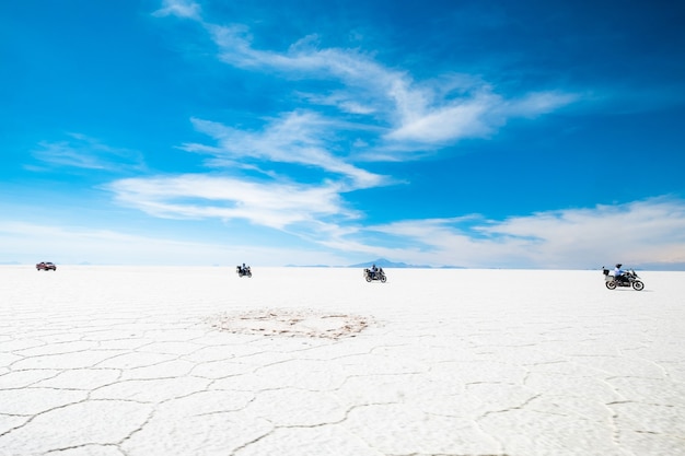 Groupe de motards et de voiture parmi le soleil salar de uyuni