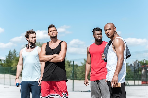 Groupe multiculturel de beaux hommes en vêtements de sport debout sur le terrain