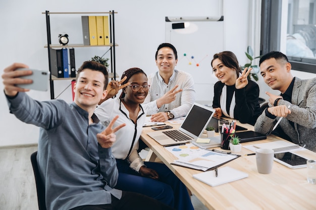 Groupe multiculturel de gens d'affaires professionnels faisant selfie dans un bureau moderne