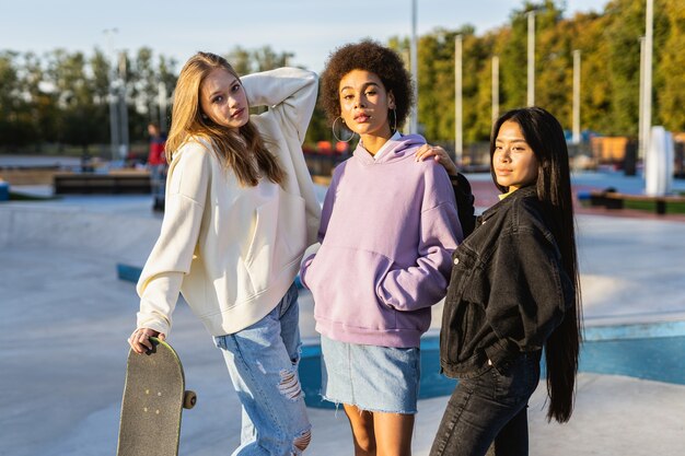 Groupe multiculturel de jeunes amis se liant à l'extérieur et s'amusant - Des adolescents cool et élégants se réunissant au skate park urbain