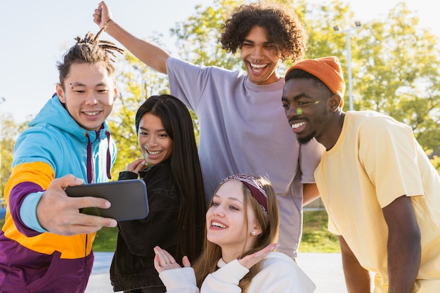 Photo groupe multiculturel de jeunes amis se liant à l'extérieur et s'amusant - des adolescents cool et élégants se réunissant au skate park urbain