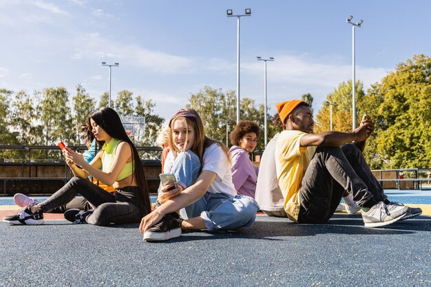 Groupe multiculturel de jeunes amis se liant à l'extérieur et s'amusant - Des adolescents cool et élégants se réunissant au skate park urbain