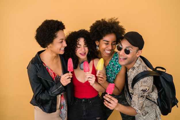 Groupe multiethnique d'amis appréciant l'été tout en mangeant des glaces.