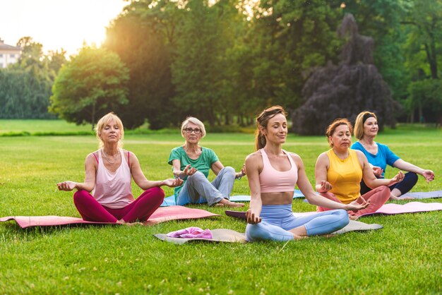 Groupe multiethnique de femmes âgées s'entraînant dans un parc avec un instructeur de fitness - Personnes âgées actives faisant du sport dans la nature