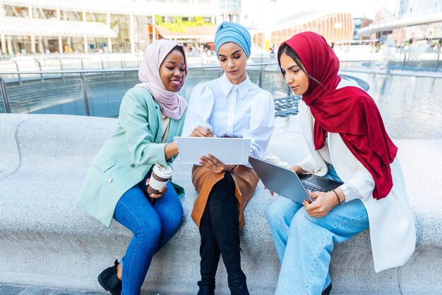 Groupe multiethnique de filles musulmanes portant des vêtements décontractés et des liens traditionnels avec le hijab et s'amusant à l'extérieur - 3 jeunes filles arabes