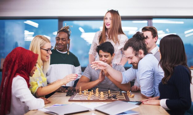 un groupe multiethnique de gens d'affaires jouant aux échecs tout en faisant une pause dans un bureau de démarrage moderne