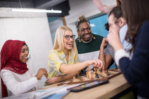 un groupe multiethnique de gens d'affaires jouant aux échecs tout en faisant une pause dans un bureau de démarrage moderne