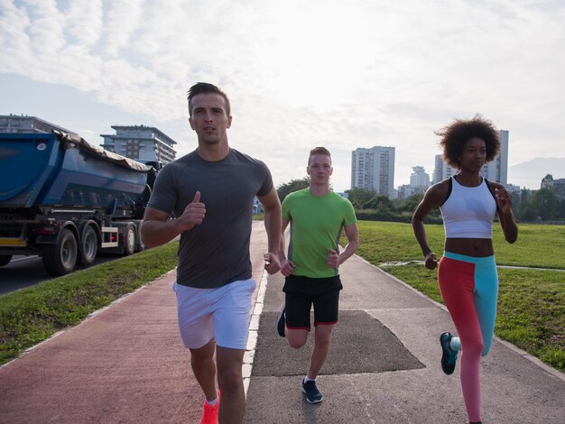 groupe multiethnique de jeunes sur le jogging beau matin alors que le soleil se lève dans les rues de la ville