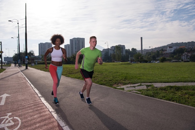 groupe multiethnique de jeunes sur le jogging beau matin alors que le soleil se lève dans les rues de la ville