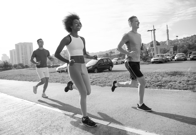 groupe multiethnique de jeunes sur le jogging beau matin alors que le soleil se lève dans les rues de la ville