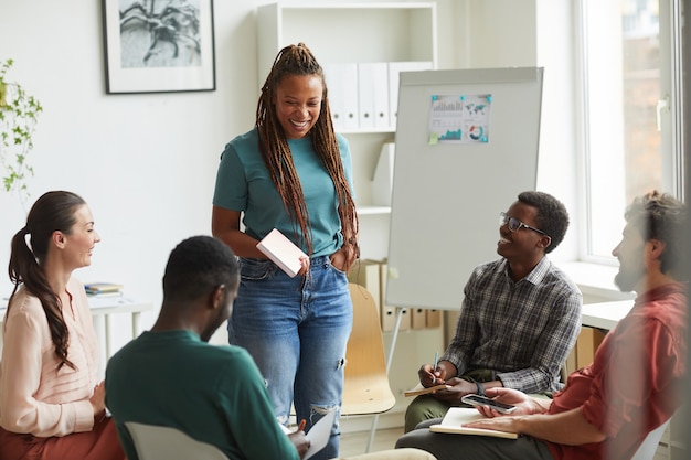 Groupe Multiethnique De Personnes Assises En Cercle Tout En Discutant Du Projet D'entreprise Au Bureau, Se Concentrer Sur Une Femme Afro-américaine Souriante Parlant à Des Collègues