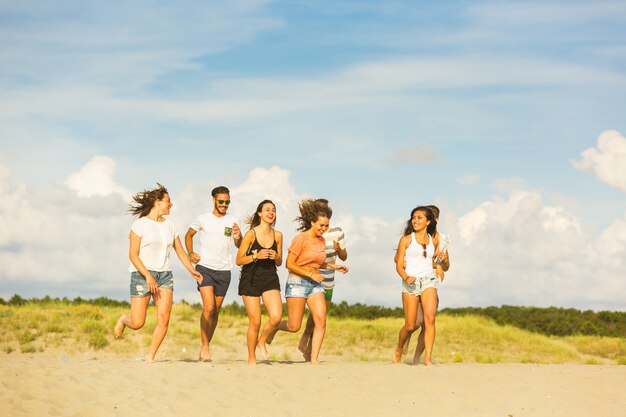 Groupe multiracial d&#39;amis en cours d&#39;exécution sur la plage