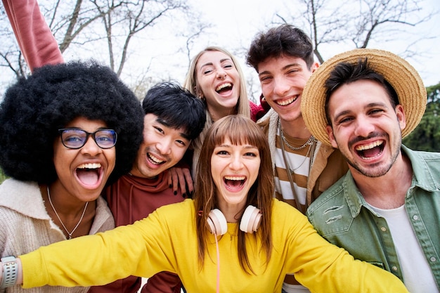 Un groupe multiracial d'amis heureux prenant un selfie dans un parc urbain grands sourires et bons moments
