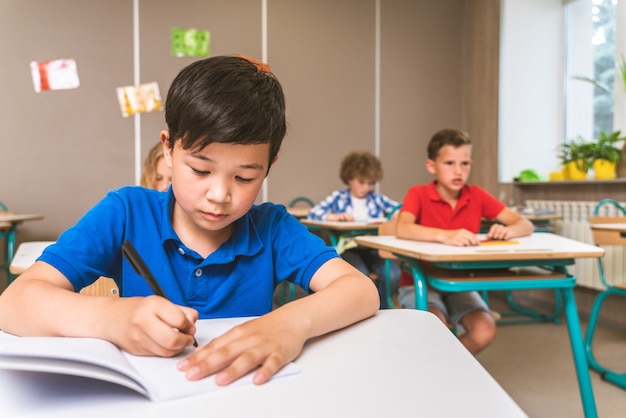 Groupe multiracial d'enfants à l'école primaire - Des écoliers enjoués profitant du temps scolaire et des cours avec l'enseignant et les camarades de classe