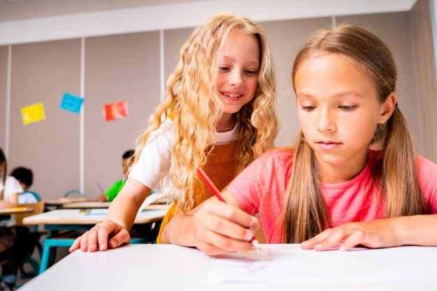 Groupe multiracial d'enfants à l'école primaire - Des écoliers enjoués profitant du temps scolaire et des cours avec l'enseignant et les camarades de classe