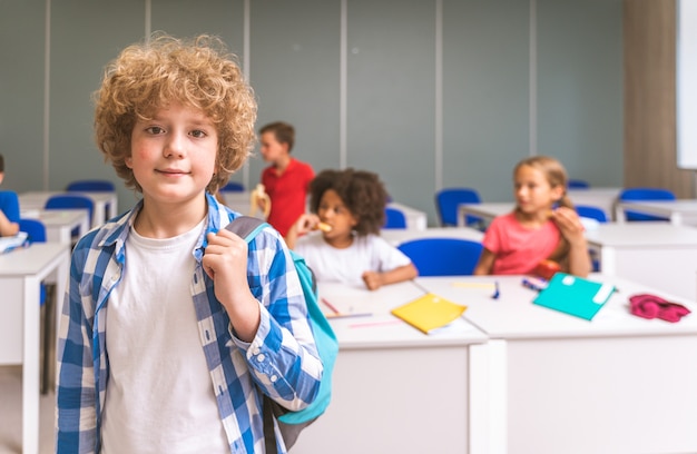 Groupe multiracial d'enfants à l'école primaire - Des écoliers enjoués profitant du temps scolaire et des cours avec l'enseignant et les camarades de classe