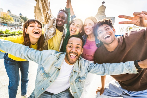 Groupe multiracial de personnes avec les bras en l'air célébrant souriant à la caméra à l'extérieur