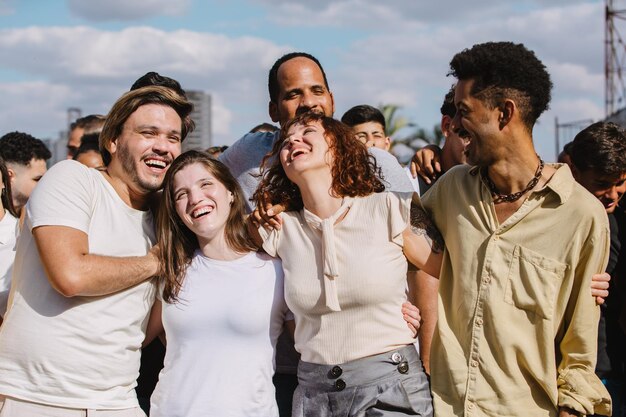 Un groupe multiracial s'embrasse en souriant dans la foule.