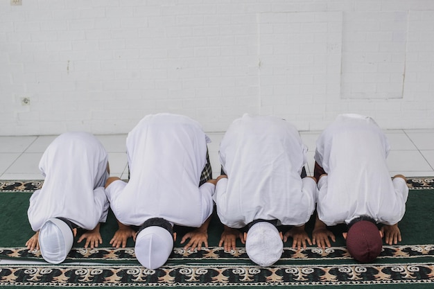 Un groupe de musulmans prient avec des mouvements de prosternation dans la mosquée