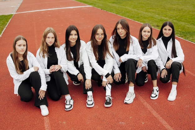 Un groupe de nombreuses adolescentes heureuses vêtues de la même tenue s'amusant et posant dans un stade près d'un collège Concept d'amitié moments de bonheur Amitié scolaire