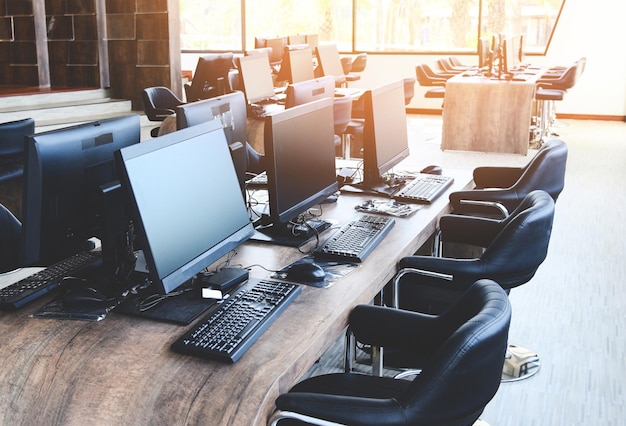 Groupe d'ordinateurs avec moniteur soigneusement placé dans un laboratoire informatique, salle informatique dans le bureau moderne avec fenêtres