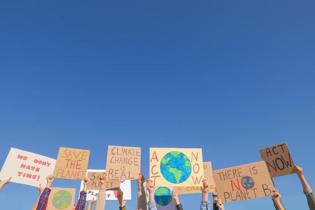 Groupe de personnes avec des affiches protestant contre le changement climatique à l'extérieur libre