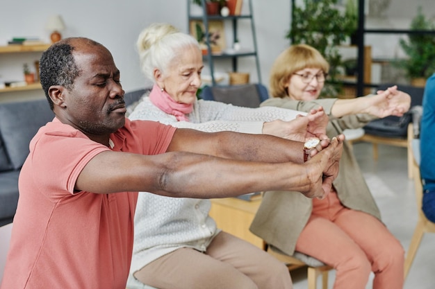 Groupe de personnes âgées faisant des exercices du matin ensemble dans la salle