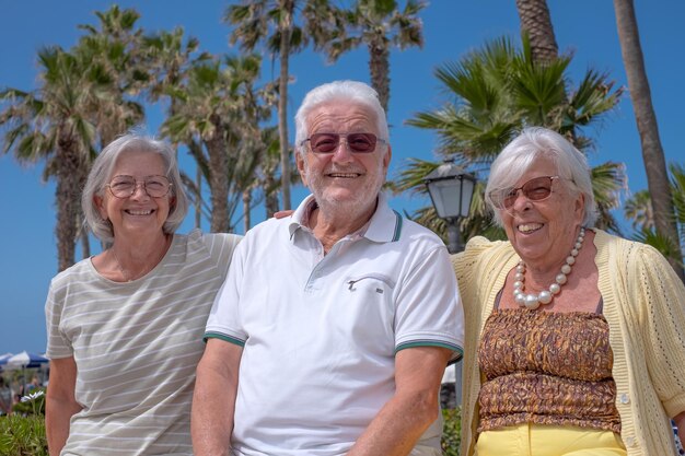 Groupe de personnes âgées heureuses assises sous le soleil, profitant des vacances en mer et de la retraite en toute liberté