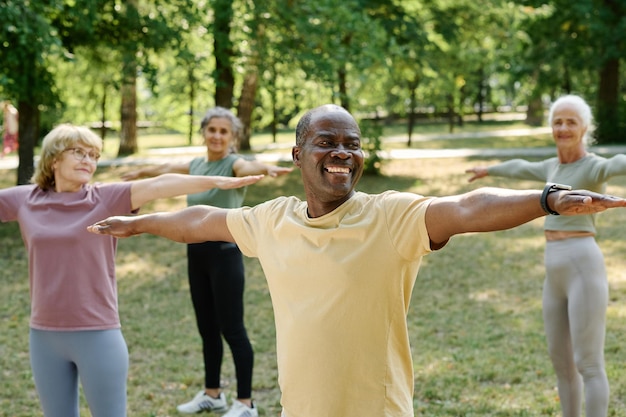 Groupe de personnes âgées heureuses exerçant dans le parc le matin