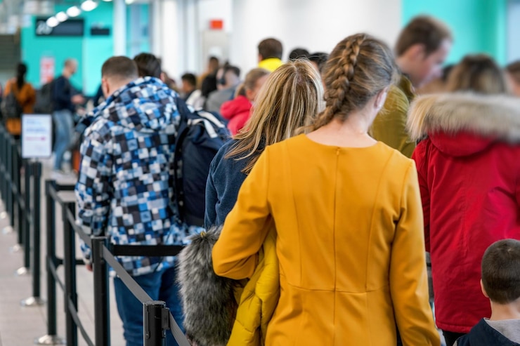 Photo groupe de personnes anonymes attendant à la porte de l'aéroport pour monter à bord d'un avion, foule en file d'attente vue de derrière.