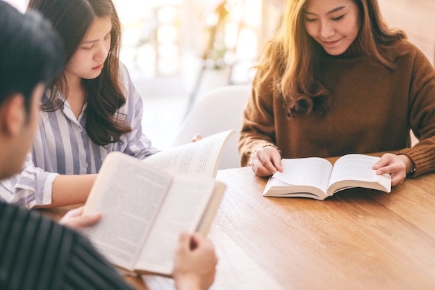 Groupe de personnes assises et apprécié la lecture d'un livre ensemble sur une table en bois