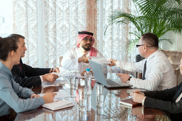 Un groupe de personnes assises autour d'une table pendant la discussion de documents