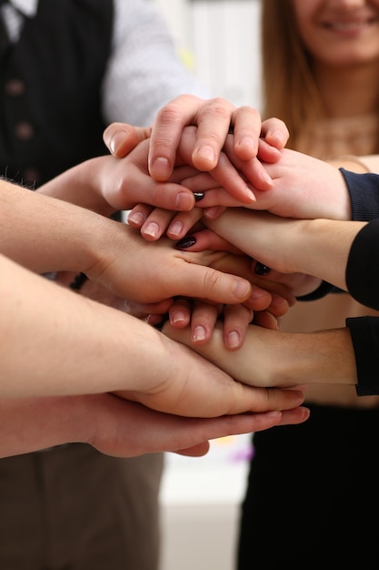 Groupe de personnes en costume croisé les mains en tas pour gagner