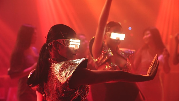Un groupe de personnes danse dans une discothèque au rythme de la musique d'un DJ sur scène