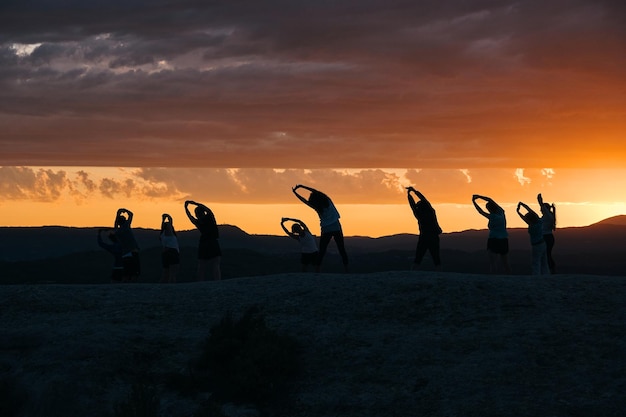 Un groupe de personnes faisant du yoga devant un coucher de soleil