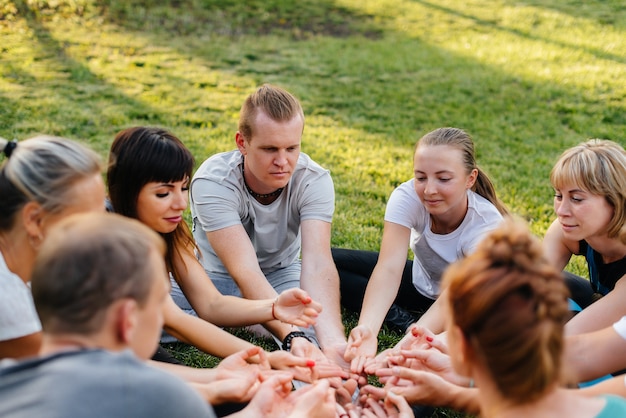 Un groupe de personnes fait du yoga en cercle en plein air au coucher du soleil. Mode de vie sain, méditation et bien-être.