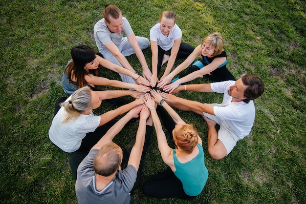 Un groupe de personnes fait du yoga en cercle en plein air au coucher du soleil.