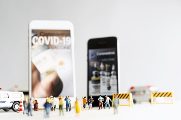 Groupe de personnes (figurine) regardant sur smartphone pendant l'application du vaccin COVID