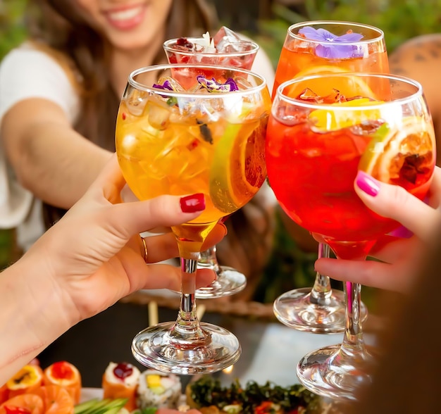 Un groupe de personnes grillant des boissons avec l'un d'eux tenant un verre avec des oranges et des tranches de citron.