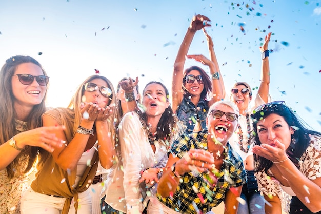 Groupe de personnes heureuses d'âges mixtes de générations de femmes s'amusant tous ensemble pendant la fête de célébration - vue sur les démons qui soufflent. confettis colorés et rire beaucoup en amitié