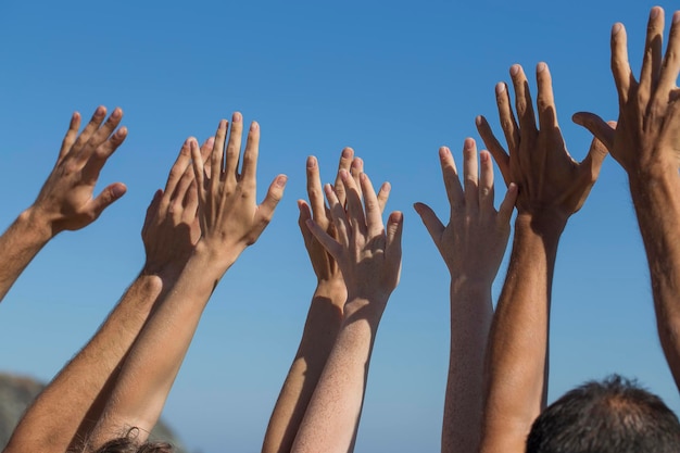 Photo un groupe de personnes lève les mains en l'air dans le ciel bleu