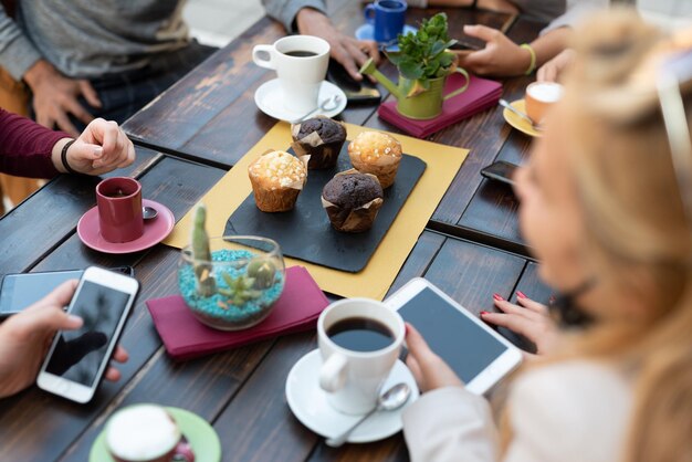 Groupe de personnes mangeant des muffins et buvant du café au petit-déjeuner